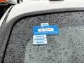 A 2015 Ford F-550 with raindrops on the windshield displaying a blue 2025 certificate of approval sticker and two blue month stickers for January and February