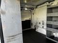 Interior view of a 2017 Ford Transit cargo van with metal shelving units on one side and a spacious empty area for storage