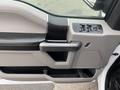 The interior door panel of a 2017 Ford F-150 featuring a black and gray design with a door handle window controls and a speaker grille