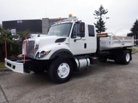 A 2010 International 7300 truck in white with a flatbed and wooden materials visible in the cargo area