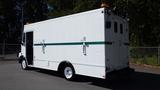 A white 2004 Freightliner MT45 vehicle with a green stripe on the side and a rear door featuring two handles