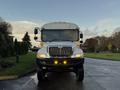 A 2015 International 3000 school bus with a white exterior and yellow lights on the front facing directly towards the viewer