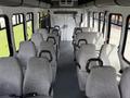 Interior of a 2010 Ford Econoline passenger van featuring multiple rows of gray upholstered seats with armrests and a spacious aisle between them