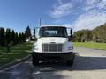 A white 2003 Freightliner M2 106 truck with a prominent grille and large headlights facing the viewer