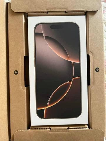 Iphone 16 Pro Max displayed in its box showing the screen design with abstract shapes in dark tones