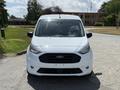 A white 2021 Ford Transit Connect van facing forward showcasing its front grille headlights and distinctive Ford badge