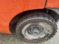 Close-up of a wet tire on a 2011 Toyota 028FG15 forklift featuring a sturdy tread pattern and metallic wheel rim