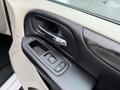 Close-up of the door handle and power window controls of a 2017 Dodge Grand Caravan interior with a textured surface and chrome accents