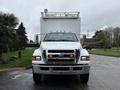 A white 2011 Ford F-650 with a large cargo box on the back and prominent front grille visible
