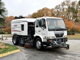 A 2009 UD Trucks UD 3300 street sweeper featuring a white and red body with front suction hoses and side broom attachments