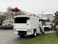 A white 2020 International MV607 bucket truck with an extended hydraulic lift and a closed utility box at the rear