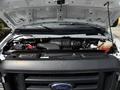 A 2017 Ford Econoline with its hood raised showing the engine compartment and various components like the air intake coolant reservoir and battery