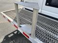 A metallic step attached to the back of a 2008 Ford Econoline with a textured surface and two vertical supports
