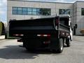 A 2015 Mitsubishi Fuso FE dump truck with a black bed and visible rear lights parked at an angle