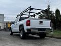 A white 2018 GMC Sierra 1500 truck with a black ladder rack attached to the bed positioned at an angle