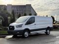 A 2023 Ford Transit van in white with a black grille and wheels parked on a street