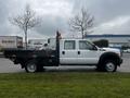 A 2015 Ford F-550 with a flatbed and extended cab parked on a grassy area