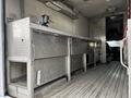 A 2006 GMC C5000 with a metallic workbench and storage compartments inside the cargo area