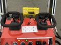 Red control panel of a 2024 AGT Industrial LRT23 featuring two black handles a tool box and various buttons and switches