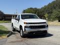 A white 2021 Chevrolet Silverado 1500 pickup truck parked facing the viewer with a silver grille and large headlights
