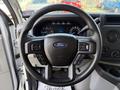 A 2023 Ford E-450 steering wheel featuring a central Ford logo and various control buttons on the sides