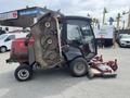A 2012 Toro Groundsmaster 5910 with an elevated cutting deck and cab featuring large wheels and multiple rotary cutting blades visible in the front