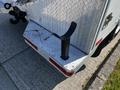 The rear step of a 2004 Freightliner M2 truck featuring a metal diamond plate surface and a black tubular handle attached to the back