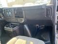 Interior dashboard of a 2016 GMC Savana featuring controls and storage compartments with a grey cloth seat visible in the foreground