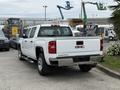 A 2016 GMC Sierra 1500 pickup truck with a white exterior and chrome accents parked in a lot viewed from the rear