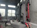 Interior seating of a 2006 E-One Typhoon featuring black adjustable seats secured with red seatbelts against a grey interior wall