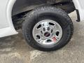 Close-up of a chrome wheel and tire of a 2022 GMC Savana showcasing a rugged tread pattern and the GMC emblem in the center
