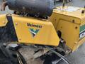 Close-up of a yellow 2014 Vermeer Corporation Sweep Stump Cutter with a prominent logo and engine section visible