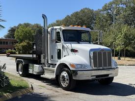 A 2019 Peterbilt 337 truck with a flatbed and chrome accents parked on a street
