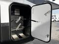 A close-up view of the exterior storage compartment of a 2021 Grand Design Recreational 311BHS with an open door revealing a black interior and metal brackets inside