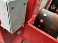 A close-up of a red component of a 2014 John Deere 1585 Terrain Cut featuring a metal panel with the logo Kraloy and several visible bolts and a connector