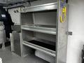 A metal shelving unit with three open shelves and a side compartment inside the cargo area of a 2019 Mercedes-Benz Metris