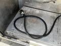 A thick black hose coiled on a metallic surface inside a vehicle with a connector at one end