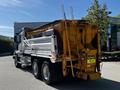 A 2005 Volvo VND 122 truck with a silver and yellow dump bed designed for carrying materials and equipped with a warning sign to maintain distance