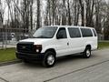 A white 2011 Ford Econoline van parked on a street with a simple design and large side windows