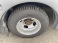 A close-up of the tire and wheel of a 2016 Chevrolet Express showing a silver steel rim and a black tire with visible tread patterns