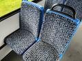 A blue and gray patterned seat in a vehicle designed for public transportation with a comfortable curved back and armrest