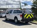 A white 2016 Ford F-150 pickup truck with a black and yellow striped tailgate and a 4x4 label on the rear left fender