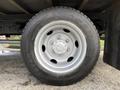 A silver wheel with a black tire mounted on a 2014 Hino 195 depicted from a side angle