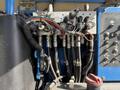 A close-up of the hydraulic control panel and hoses of a 2012 Genie Z 45/25 with various knobs and electrical connections visible