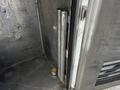 A metal compartment with two cylindrical pipes standing vertically and a small canister at the bottom