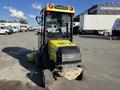 A yellow 2010 Kubota F3990 with a clear cab and mower attachment, featuring a distinctive front hood design and large rear wheels