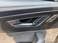 Close-up of the interior door panel of a 2020 Audi RS featuring a carbon fiber finish and window control buttons