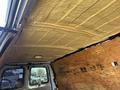 The interior of a 2012 Chevrolet Express van showing a foam insulation layer on the ceiling with exposed plywood walls