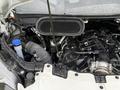 A 2023 Ford Transit engine compartment featuring an exposed engine with various components including hoses and a coolant reservoir