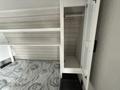 Interior view of a 2022 Keystone Hideout RDWE 20RDWE showing a bed with a patterned cover and cabinet shelving above